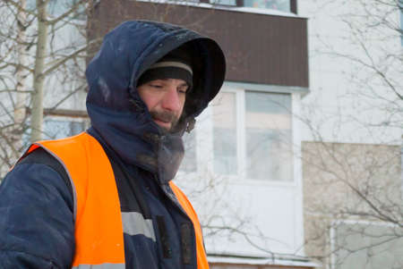 Worker in a blue jacket with a hood and a reflective vest at the workplace