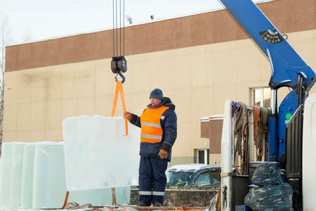 Portrait of a working installer in a reflective vest while unloading ice platesの写真素材