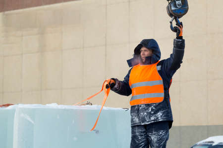 Portrait of a working installer in a reflective vest while unloading ice platesの写真素材