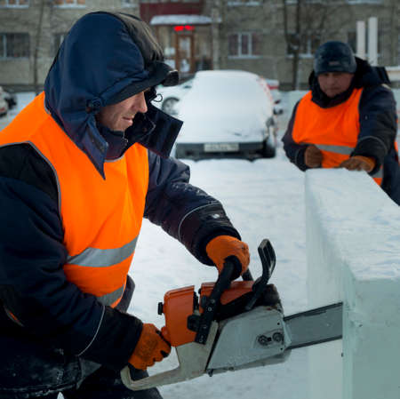 Worker installer in orange reflective vest chainsaw sets ice plateの写真素材