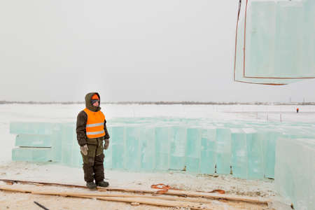 Worker slinger in orange reflective vest and helmet unloads ice panelsの写真素材