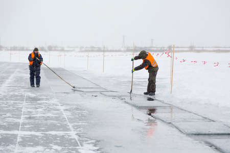 Installers in life jackets rafting ice panels to the lane with the beogramsの写真素材