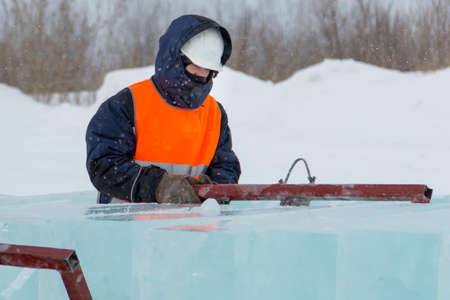 Worker slinger in orange reflective vest and helmet unloads ice panels