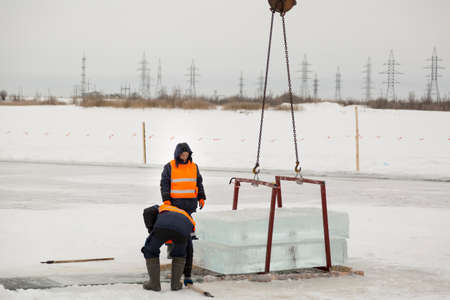 Workers observe the lifting of ice plates with a lane crane using metal framesの写真素材