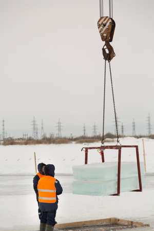 Workers observe the lifting of ice plates with a lane crane using metal framesの写真素材