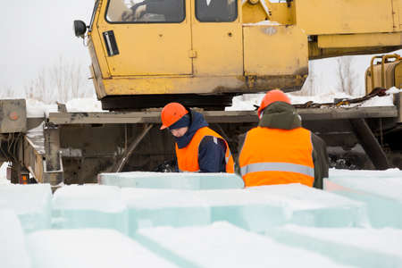 Worker slingers in orange reflective vests and helmets ship ice panels