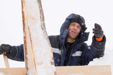 An installer at the construction of wooden formwork from boards