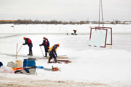 Worker slingers in orange reflective vests and helmets ship ice panelsの写真素材