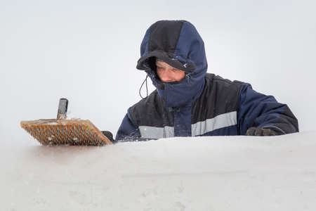 The builder cleans the ice panel with a wire brush from snowの写真素材
