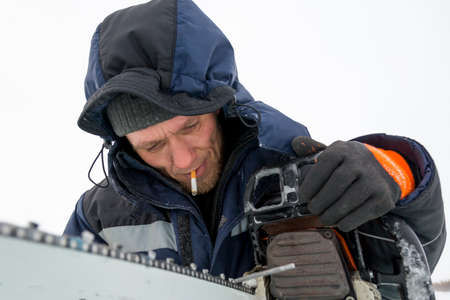 A manual file worker sharpens a chainsaw chain