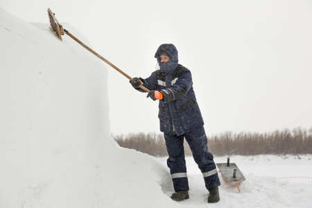 Worker removes snow from the ice panel with a metal brush