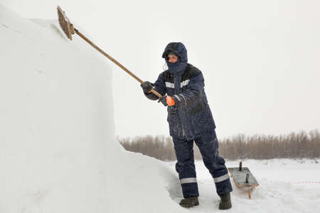 Worker removes snow from the ice panel with a metal brush