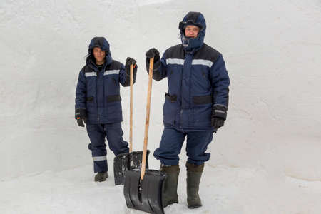 Portrait of workers with shovels in hands on a background of a snowy wallの写真素材
