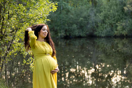 Portrait of a pregnant woman in a yellow dress in the autumn forestの写真素材