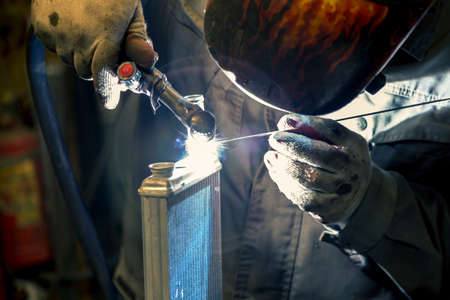 A TIG specialist welds a pipe to a small car radiator