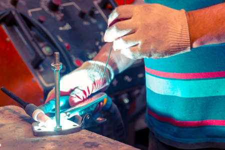TIG welder welds stud to polished stainless steel flange