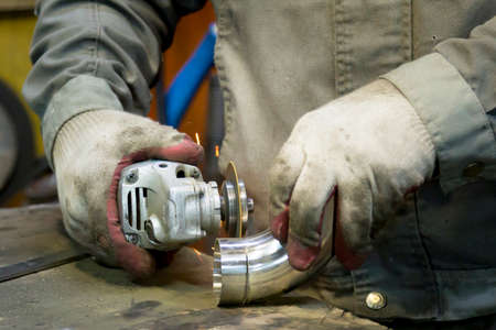A worker adjusts a fitting to a polished stainless steel pipe