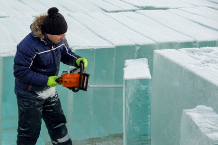 Work installer with a chainsaw in his hands undercut ice blockの写真素材