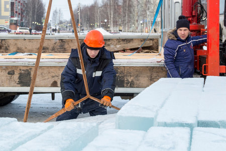 Assemblers unload ice panels from a car using a crane