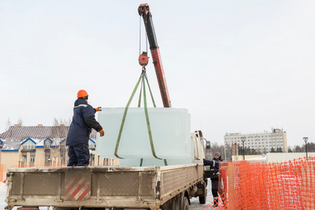 Assemblers unload ice panels from a car using a crane