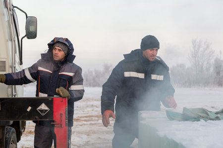 Workers load ice blocks from a car