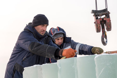 Workers load ice blocks from a car