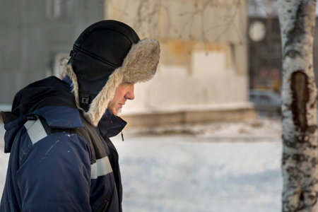 Portrait of a man in a hat with light fur with a blue winter jacket at the workplaceの写真素材
