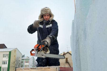 An installer in a hat with earflaps mounts the frame of a slide made of wooden beams