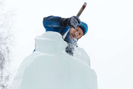 The sculptor cuts an ice figure out of a block of ice for Christmas