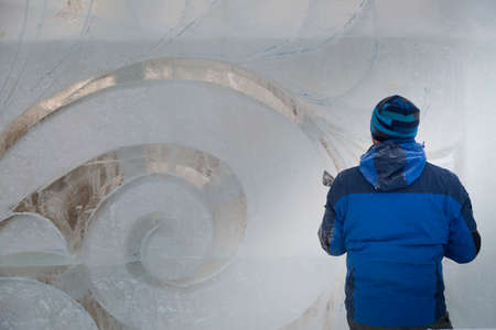 The sculptor cuts an ice figure out of a block of ice for Christmasの写真素材