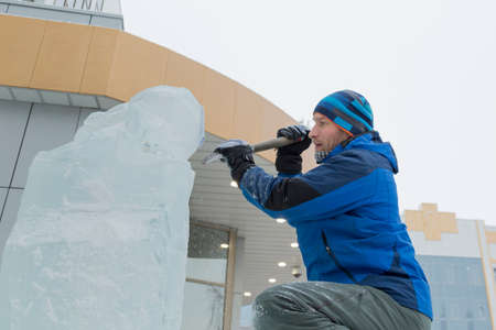 The sculptor cuts an ice figure out of a block of ice for Christmasの写真素材