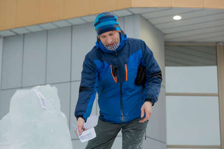 The sculptor cuts an ice figure out of a block of ice for Christmasの写真素材