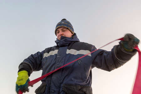 Portrait of a worker slinger in a blue jacket unloading ice blocks using a chain spider