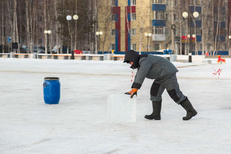 The worker pulls the ice block around the ice camp assembly site with forceps