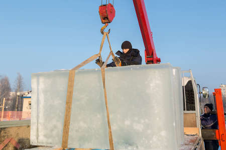 Portrait of a working assembler in a blue jacket and a knitted black hat near an ice panel