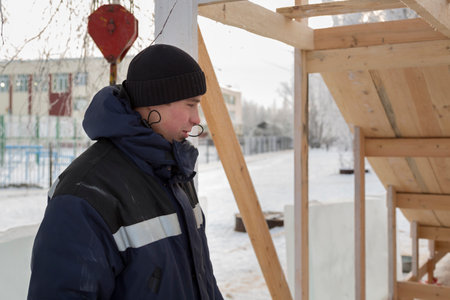 Worker assembler in jacket and black hat unloads ice blocks