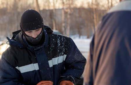 Worker assembler in jacket and black hat unloads ice blocksの写真素材