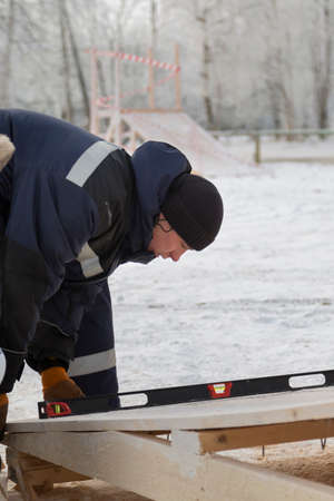 Worker assembler in jacket and black hat unloads ice blocks