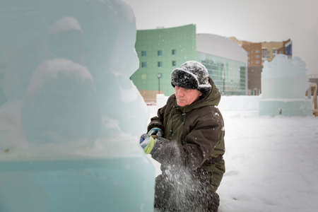 Facial portrait of a worker in a hat with earflaps busy with the arrangement of the ice townの写真素材