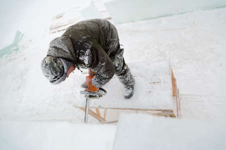 Worker with a chainsaw in hand at the assembly site