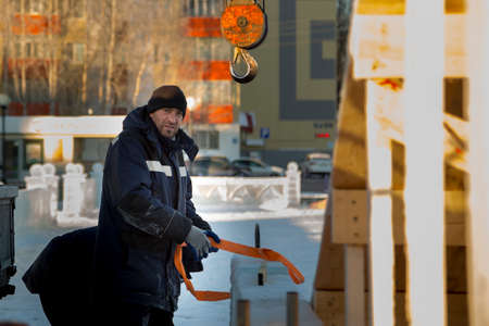 Slinger assembler in a blue jacket with a hood and a black hat unloads ice blocks