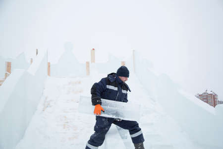 Portrait of an assembler worker in a jacket with a hood at the construction of an ice camp