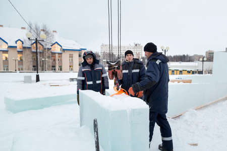 Three workers cover the frame of a wooden slide with ice panels