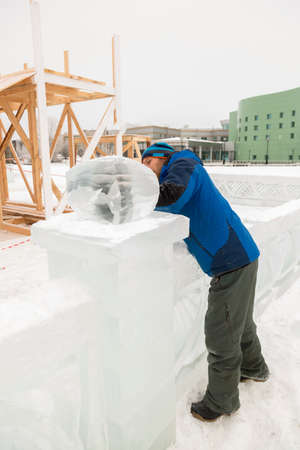 The sculptor cuts an ice figure out of ice with a chisel for Christmas