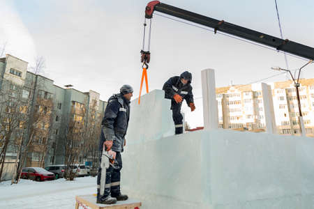 The builders of the ice town enclose the Christmas tree under construction with high green panelsの写真素材