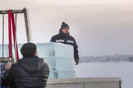 Two assembly workers unload ice plates from the body of a car