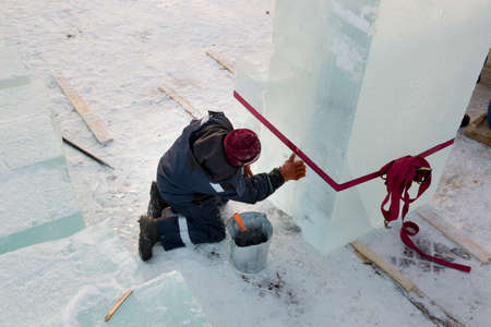 Portrait of a worker in a blue jacket with a hood at the hook of a truck craneの写真素材