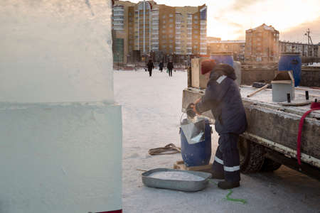 Portrait of a worker in a blue jacket with a hood at the hook of a truck craneの写真素材