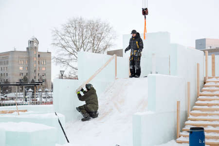 A worker with a chainsaw is talking to a partner at the ice pad.の写真素材