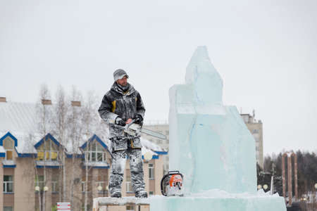 Sculptor on the scaffolding with a chainsaw next to a stalking figureの写真素材